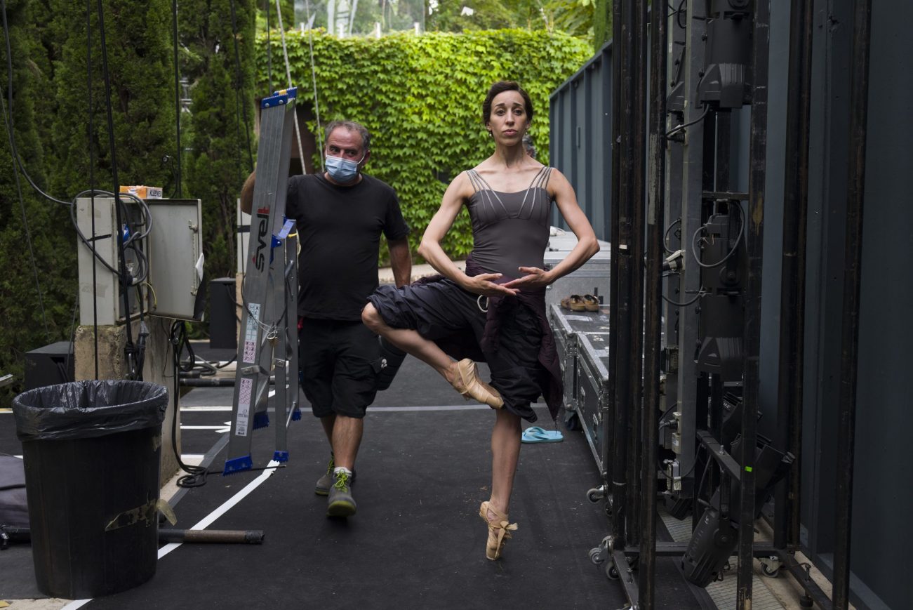 A technician passes by a dancer as she is warms up in the backstage before the rehearsal on Tuesday 21nd July, 2020 in Generalife theatre, Granada, Spain. The Generalife theatre is inside La Alhambra. Laura Len for The New York Times